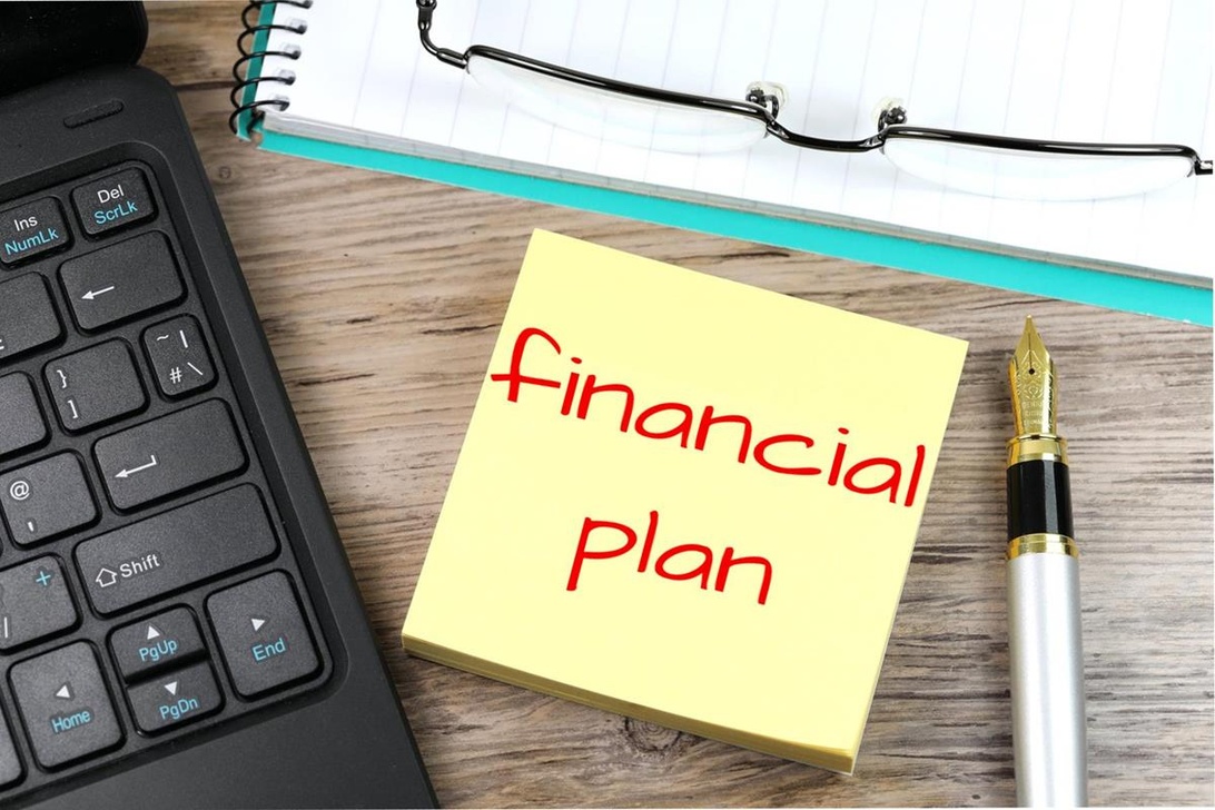 En arbetsplats med en lapp där det står 'Financial Plan', vilket visar början på en ekonomisk planering.